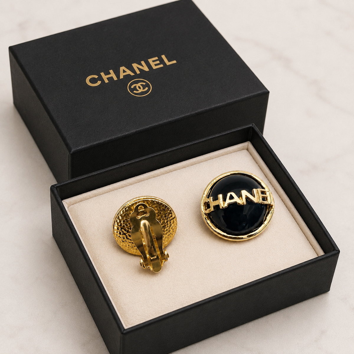 Chanel round clip-on earrings in black enamel/resin with gold-tone CHANEL lettering